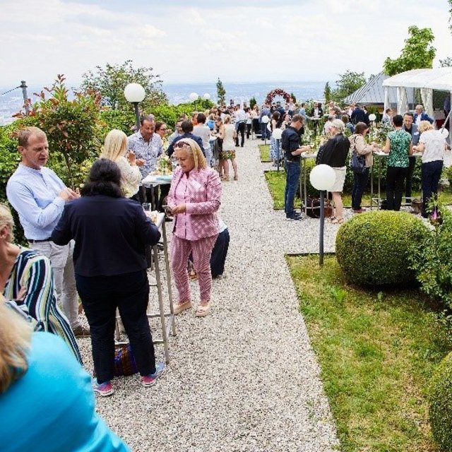 Mitarbeiter:innen beim Ausklang des Symposiums im Rosengarten mit Ausblick über Linz.